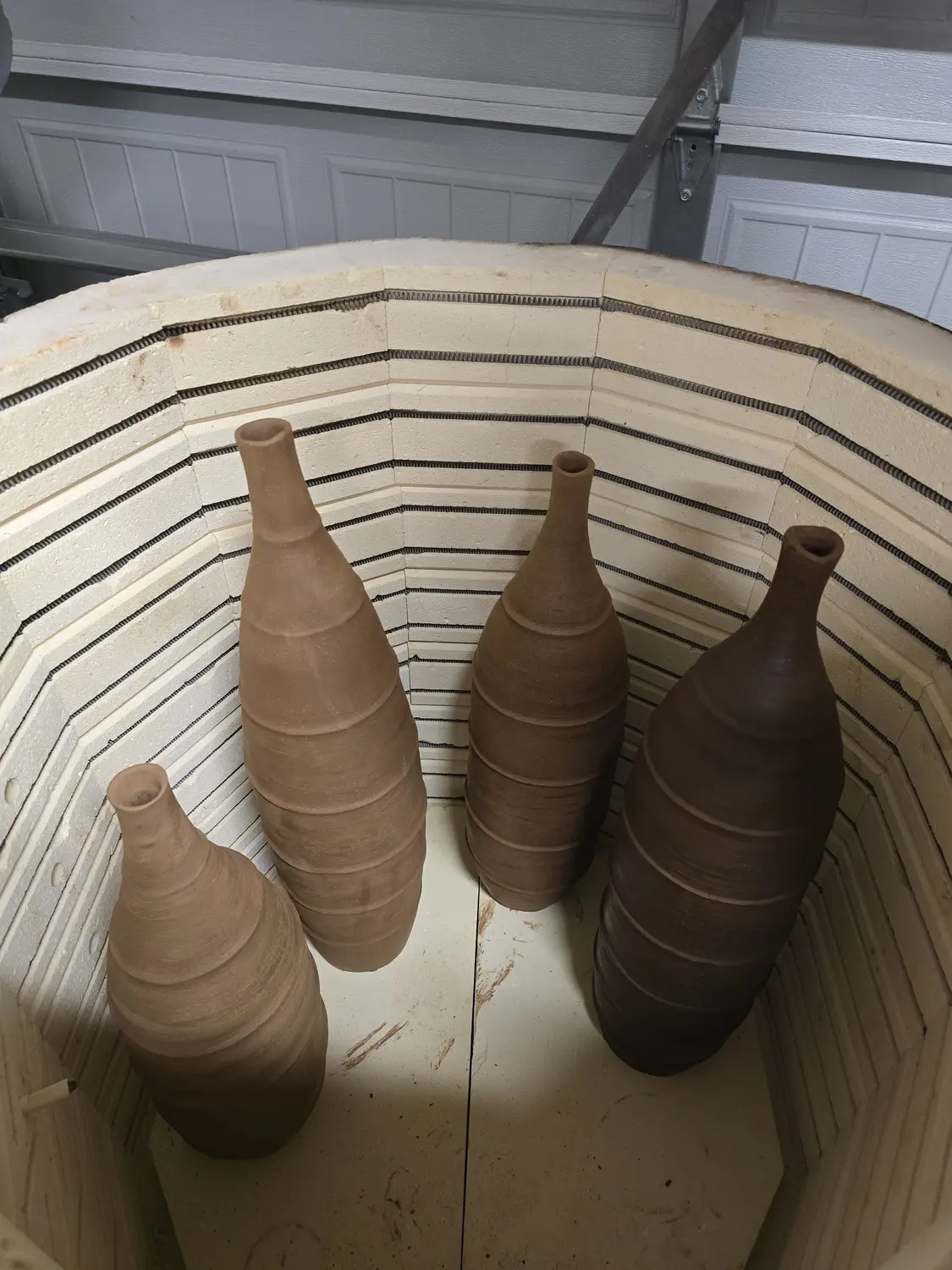 Four narrow ceramic forms arranged inside a kiln