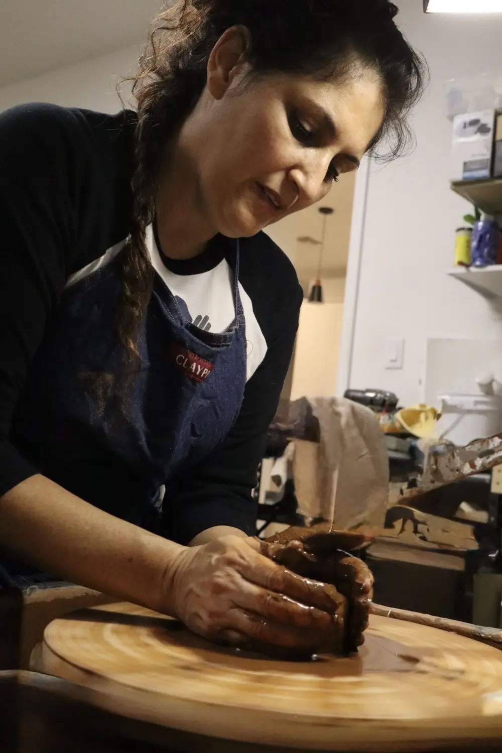 Maria shaping a clay vessel on a pottery wheel