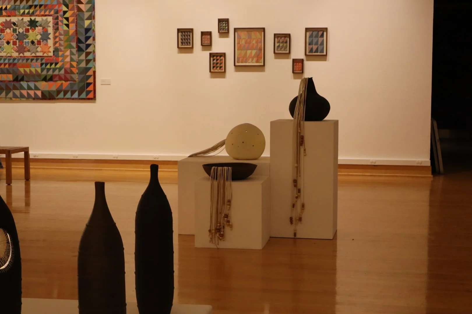 Four tall dark ceramic vessels with layered horizontal bands